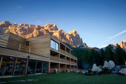 Modern houten gebouw met zonverlichte bergen en bos in het avondlicht