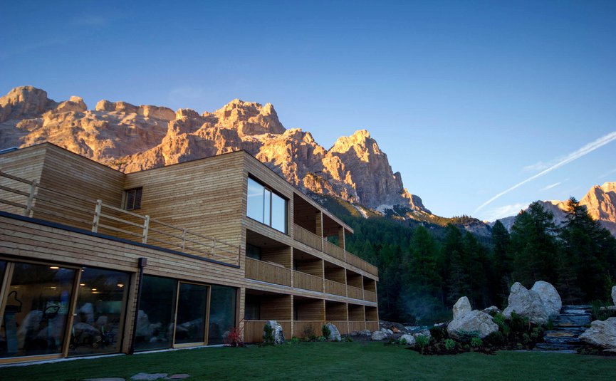 Moderner Holzbau vor sonnenbeleuchteten Bergen und Wald im Abendlicht