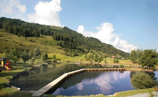Lago con pontile in paesaggio montano panoramico e cielo azzurro