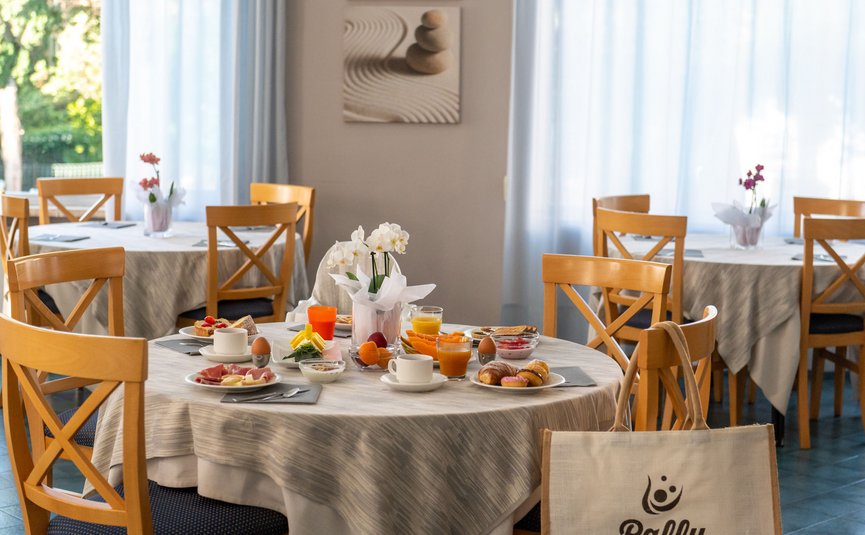 Breakfast table with coffee, juice, fruit, eggs, and pastries in cozy room