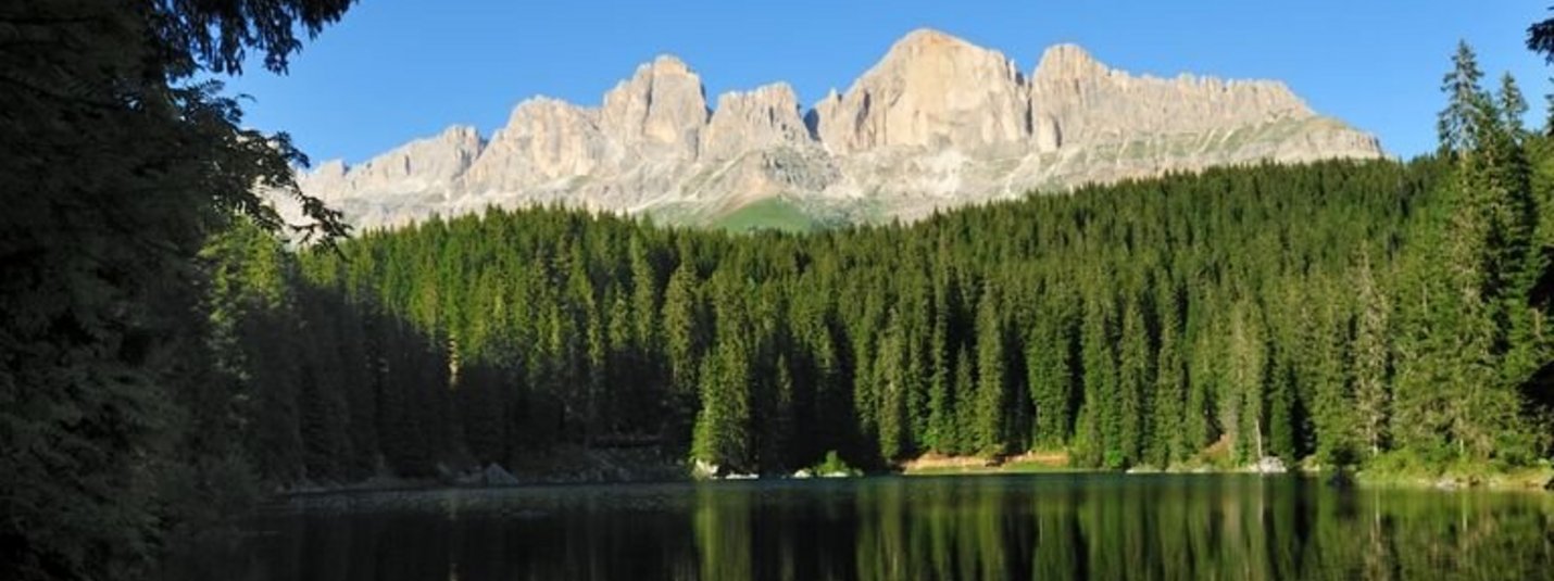 Bergspitzen und Wald spiegeln sich in einem ruhigen See