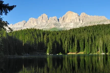 Bergspitzen und Wald spiegeln sich in einem ruhigen See