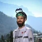 Man met fiets voor berglandschap en dorp op de achtergrond