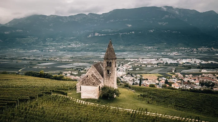 Old church on hill surrounded by vineyards with mountains in the background