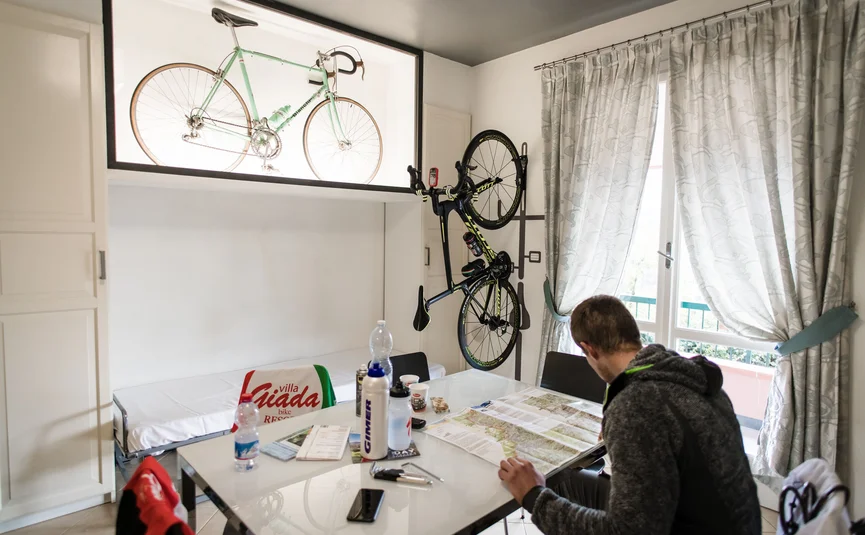 Man reading map in room with bikes and water bottles on table