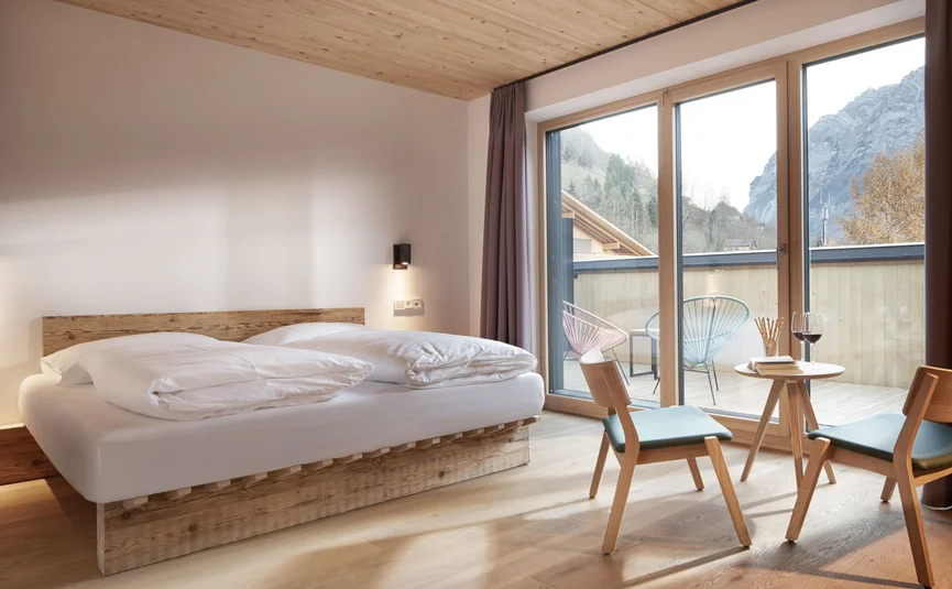 Modernes Schlafzimmer mit Holzmöbeln und Balkon mit Bergblick