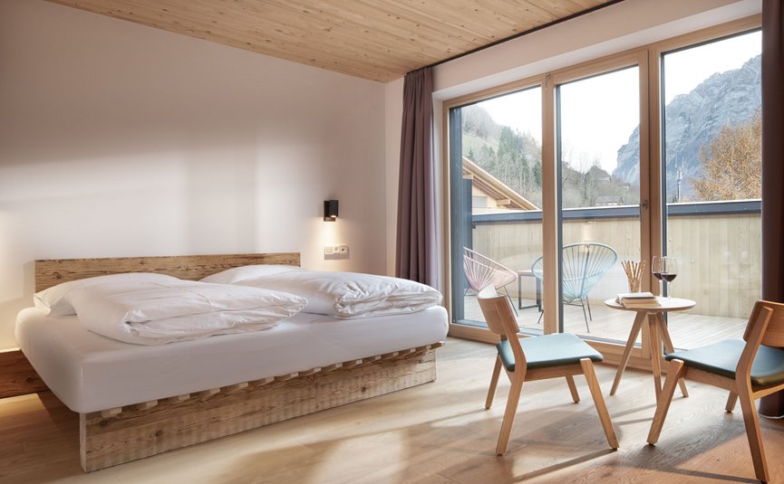 Modern bedroom with wooden furniture and balcony overlooking the mountains