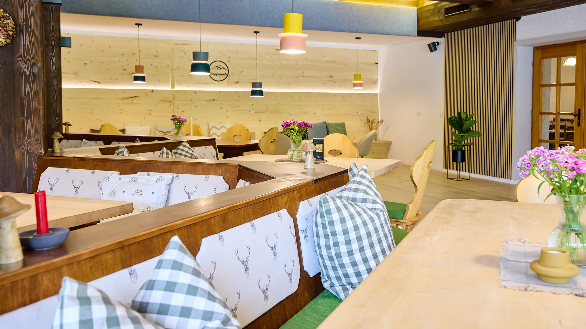 Gemütlicher Restaurantbereich mit Holzmöbeln und karierten Kissen