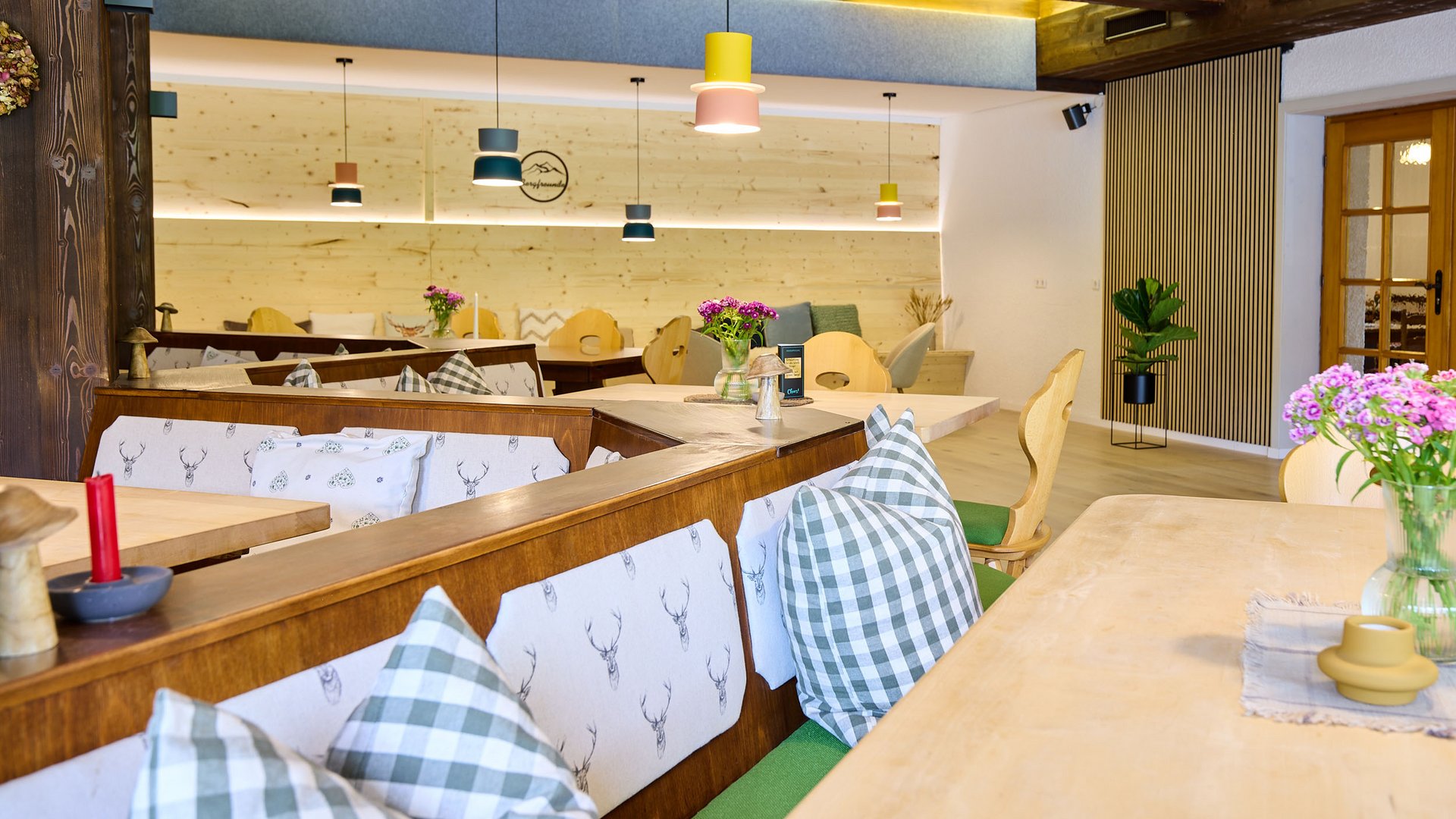 Gemütlicher Restaurantbereich mit Holzmöbeln und karierten Kissen