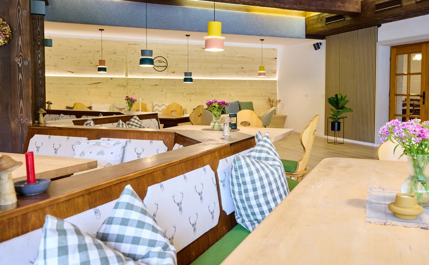 Gemütlicher Restaurantbereich mit Holzmöbeln und karierten Kissen