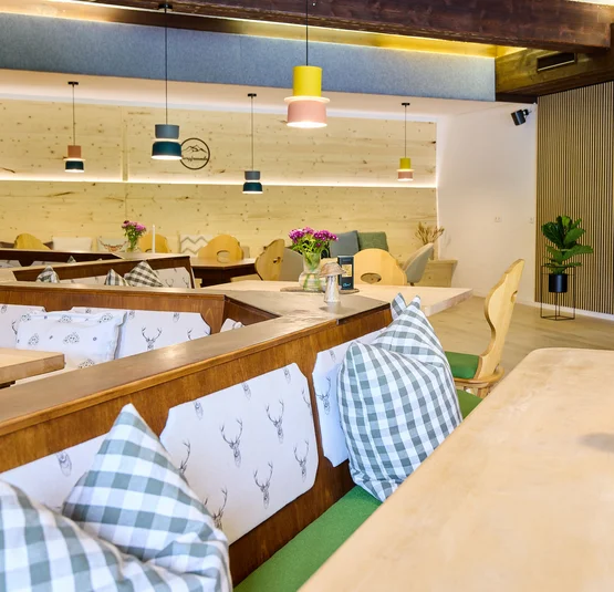Simonswald torna a San Pietro © Landhotel Fuchs Interno accogliente di un ristorante con mobili in legno e cuscini a quadri