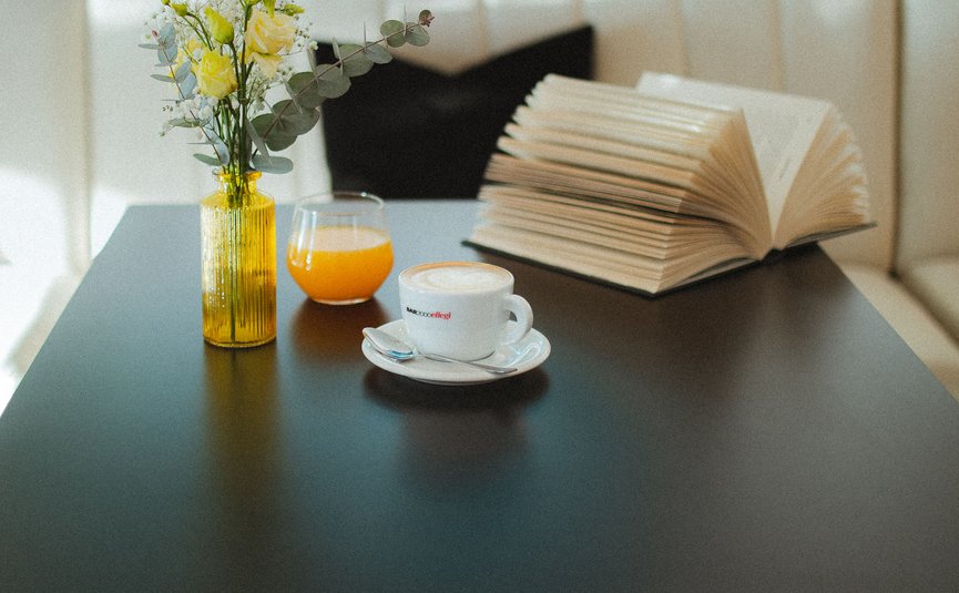 Hotel Capris **** © Hotel Capris Capodistria Boutique Zwart tafel met gele vaas, sinaasappelsap, koffie en een open boek