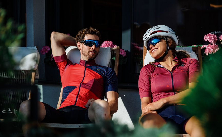 Twee fietsers ontspannen op stoelen in de zon voor een huis