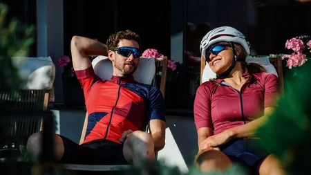 Zwei Radfahrer entspannen auf Stühlen in der Sonne vor einem Haus