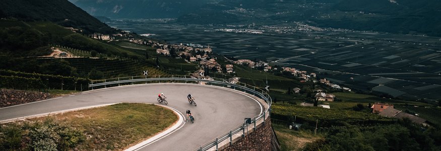 Drie fietsers op een haarspeldbocht in een bergachtig landschap