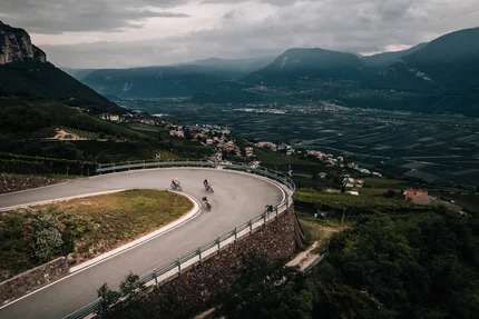 Drei Radfahrer auf einer Serpentinenstraße in bergiger Landschaft
