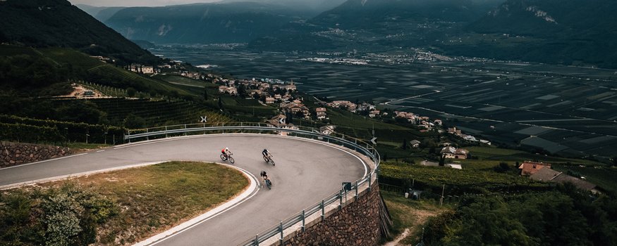 Tramin / Kalterer See © Jens Scheibe Drei Radfahrer auf einer Serpentinenstraße in bergiger Landschaft
