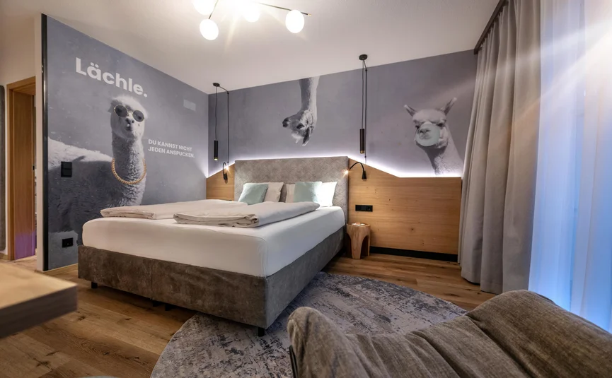 Modernes Hotelzimmer mit Bett und Wandbildern von lustigen Lamas