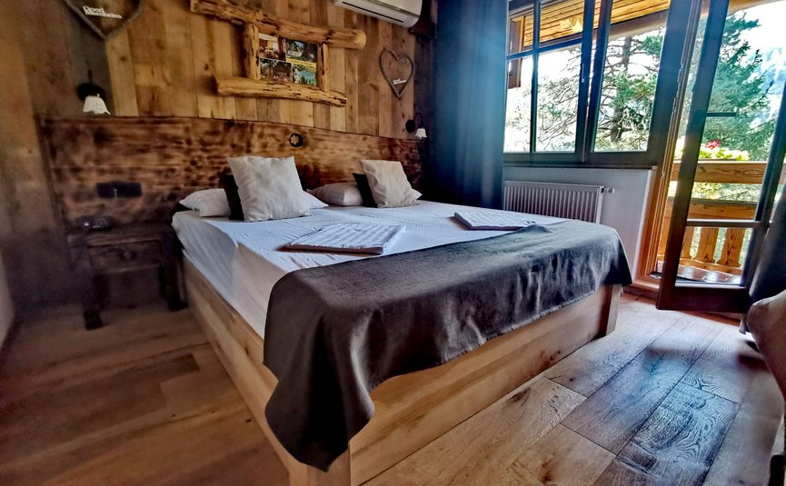 Camera da letto accogliente in legno con letto matrimoniale e vista balcone