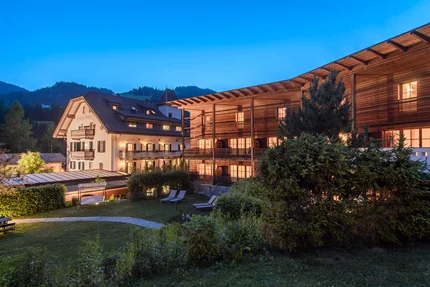 Verlichte hotels met tuin en ligstoelen bij schemering in de bergen