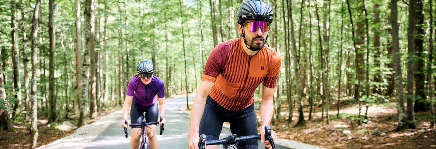 Zwei Radfahrer in Schutzhelmen fahren auf einem Waldweg