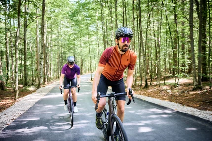 Twee fietsers met helmen rijden op een bosweg