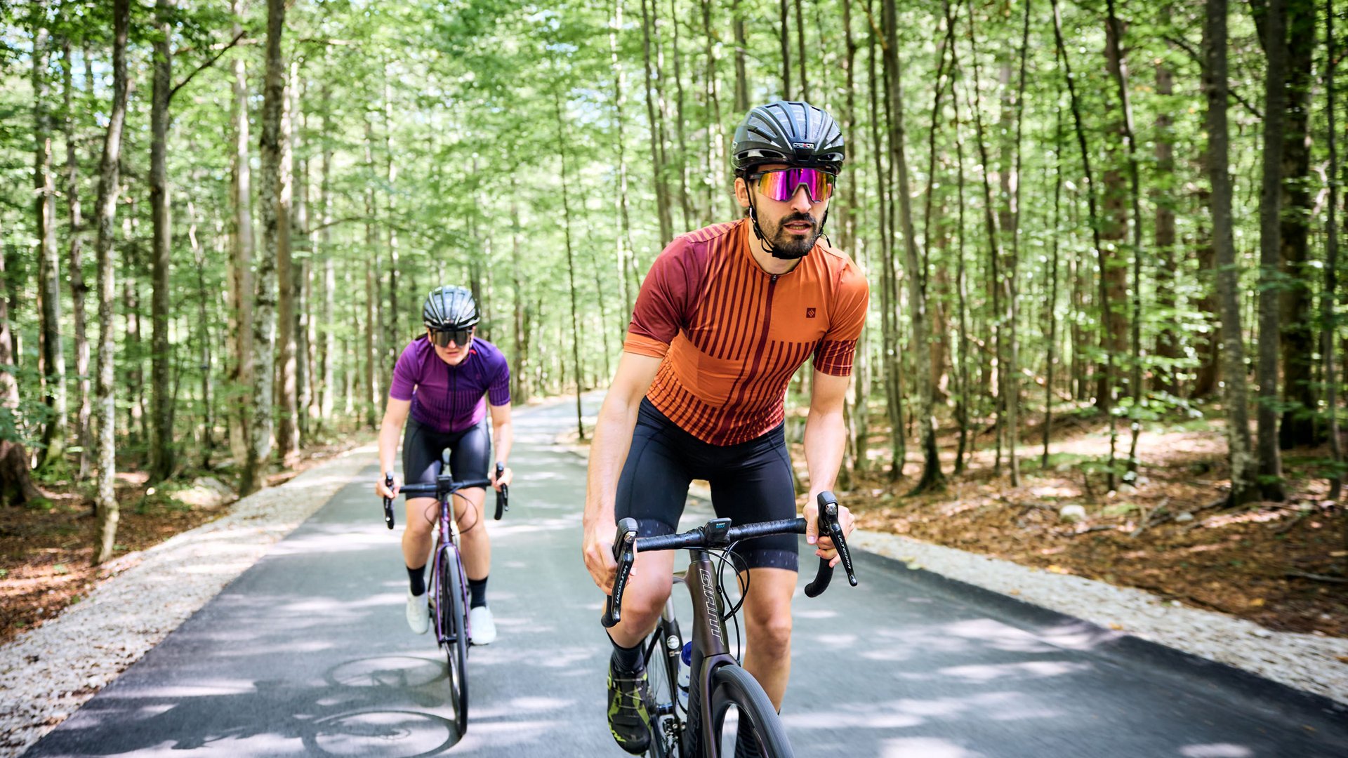 Zwei Radfahrer in Schutzhelmen fahren auf einem Waldweg