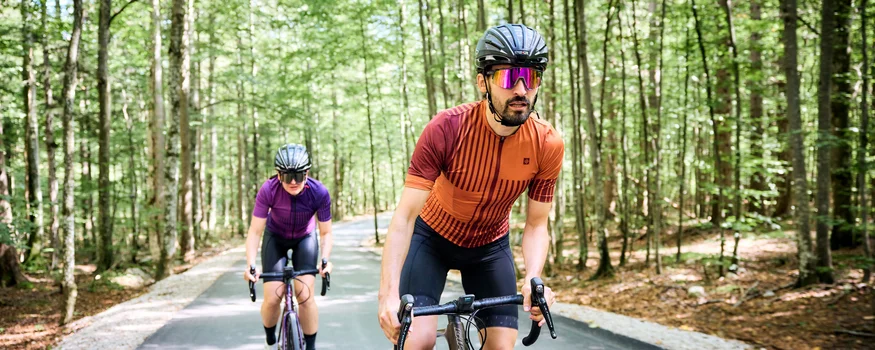 Zwei Radfahrer in Schutzhelmen fahren auf einem Waldweg