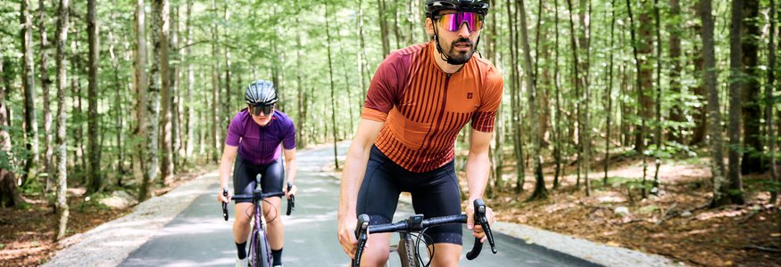 Zwei Radfahrer in Schutzhelmen fahren auf einem Waldweg