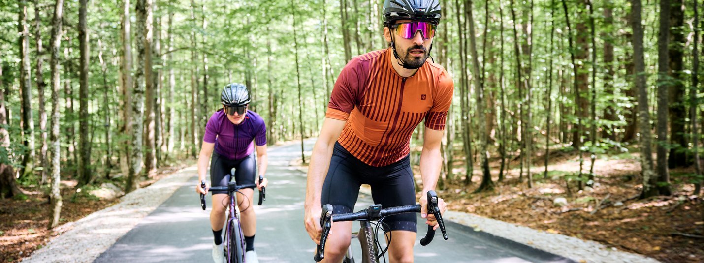 Twee fietsers met helmen rijden op een bosweg