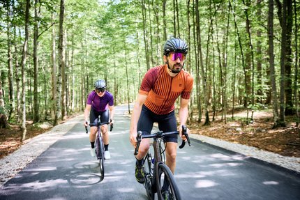 Twee fietsers met helmen rijden op een bosweg