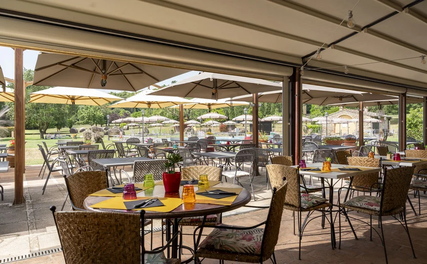 Außenrestaurant mit Tischen, Stühlen und Sonnenschirmen im Garten