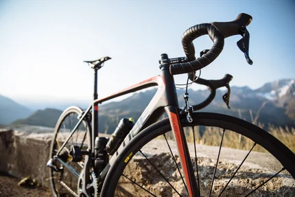 Road bike parked by stone wall with mountains in background