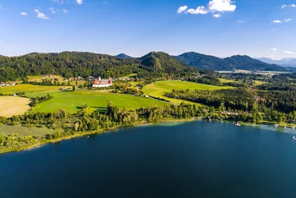 Blick auf den Schwarzsee mit grünem Ufer und Bergen im Hintergrund