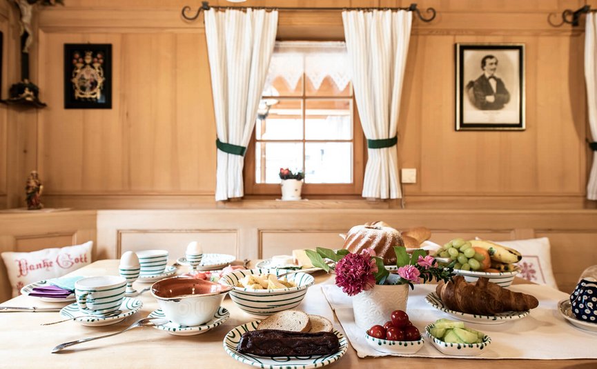 Gemütlicher Frühstückstisch mit Brot, Obst und Butter in traditioneller Holzstube