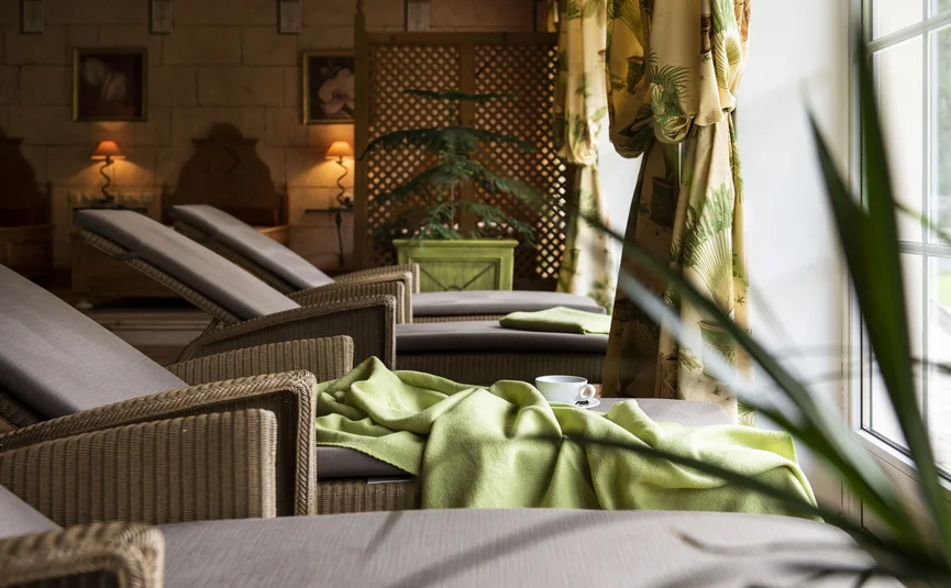 Ruheliegen mit grünem Decken und Tasse neben Fenster in einem Spa