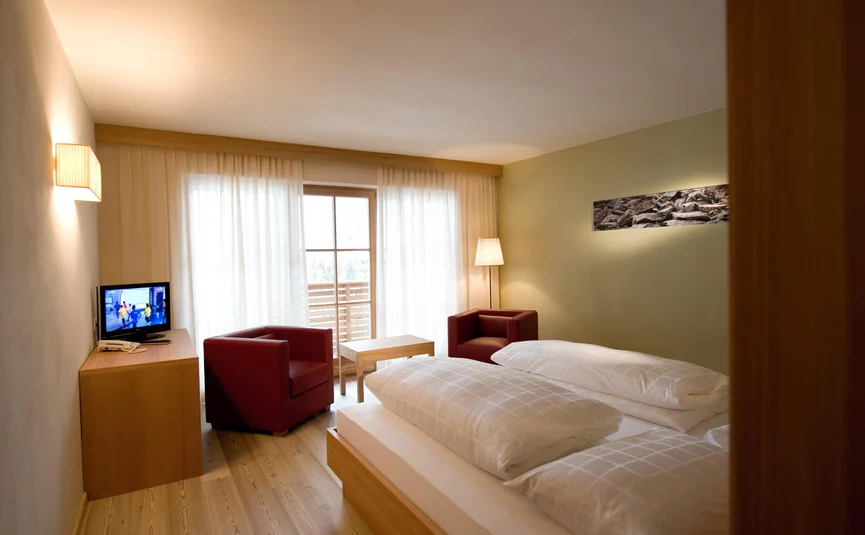 Gezellige hotelkamer met tweepersoonsbed, twee stoelen en tv