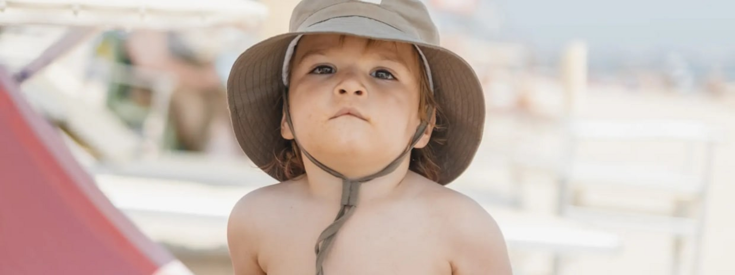 Frühling mit Ihrem vierbeinigen Freund Kleintje met zonnehoed op het strand kijkt omhoog