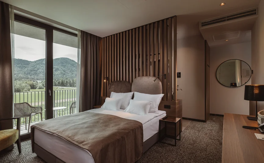 Modernes Hotelzimmer mit Doppelbett und Bergblick durch bodentiefe Fenster