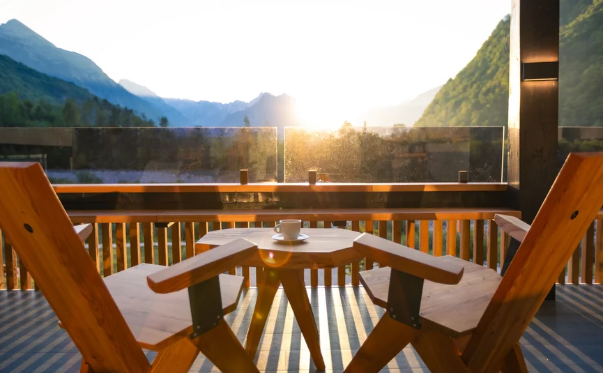 Alba sulle montagne con sedia di legno e tazza di caffè sul balcone