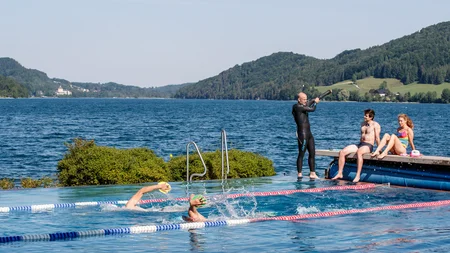 Ein Rennrad-Wochenende im SalzburgerLand – Salzkammergut © Erwin Haiden Schwimmer im Außenpool am See mit zwei Personen auf Steg und Trainer