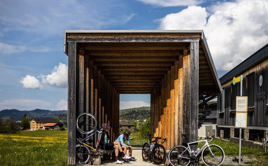 Due ciclisti si riposano in un riparo di legno sotto il sole