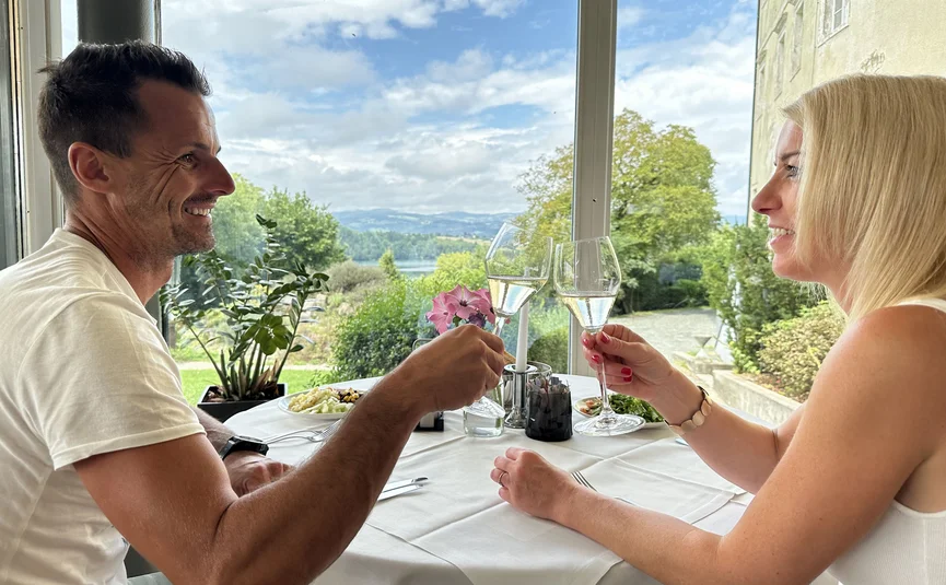 Paar stößt mit Sektgläsern in einem Restaurant mit Gartenblick an