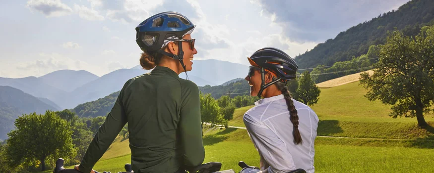 Two women with bikes in a rural, mountainous landscape