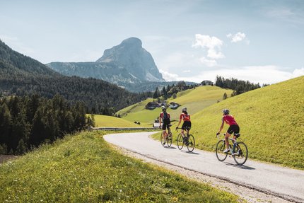 Drie fietsers op een bergweg met Alpenlandschap