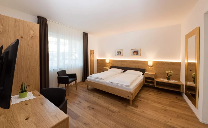 Camera d'hotel moderna con letto matrimoniale, pavimento di legno e grande specchio