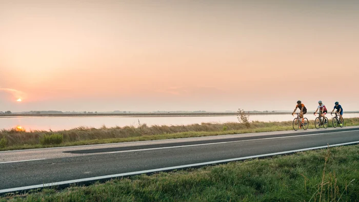 Adriatische Küste: Rennradurlaub mit Dolce Vita © Alex Moling Drei Radfahrer fahren bei Sonnenuntergang an einem Fluss entlang