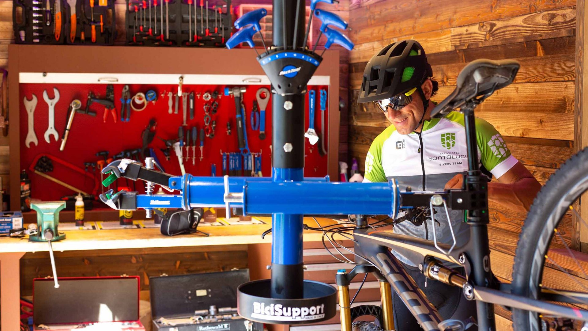 Mann mit Fahrradhelm repariert Mountainbike in Werkstatt