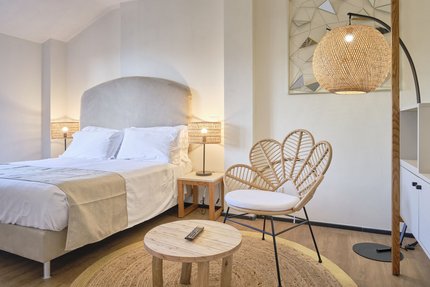 Camera da letto luminosa con letto comodo, sedia in rattan e luce calda