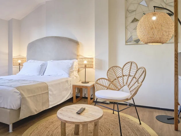Villa Giada SpEace Resort: Mit deinem Rennrad aufs Zimmer © Villa Giada spEace & Bike Resort Helles Schlafzimmer mit gemütlichem Bett, Rattanstuhl und warmem Licht